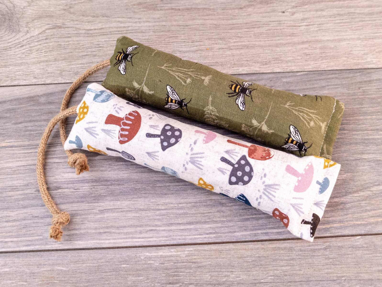 Two catnip kicker cat toys made out of a green bee fabric and white mushroom fabric.