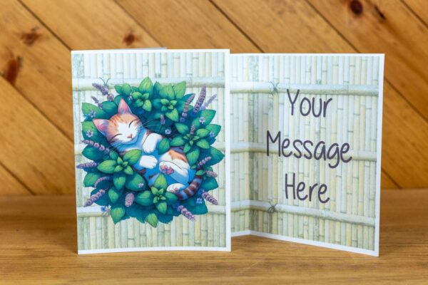 A greeting card with a cat laying in a pile of leaves on the front